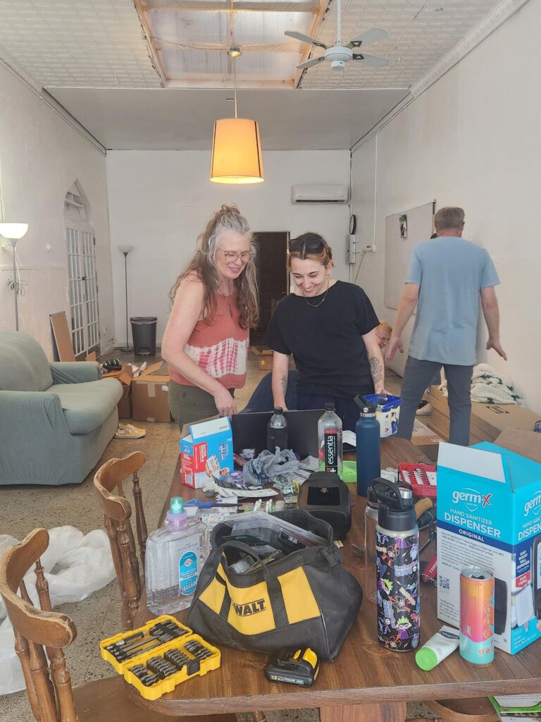 Shelby and Denise standing together looking at a laptop. The interior under construction for renovation.